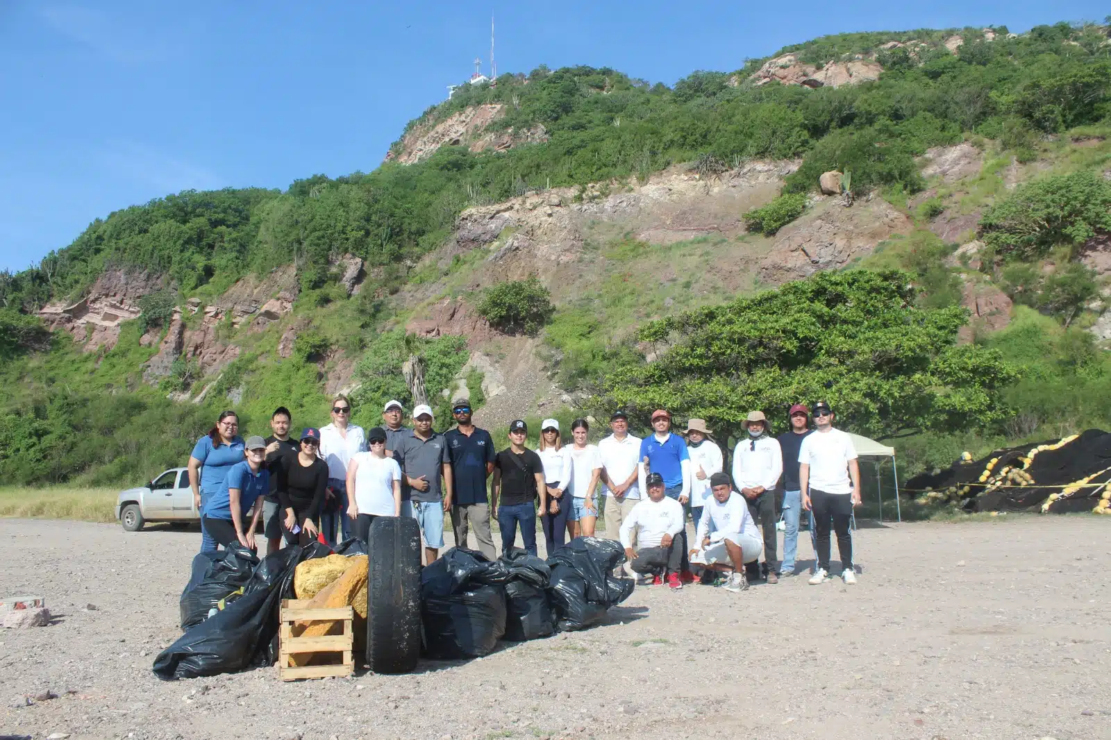 Asistentes de jornada de limpieza posando para la foto junto con los desechos acumulados