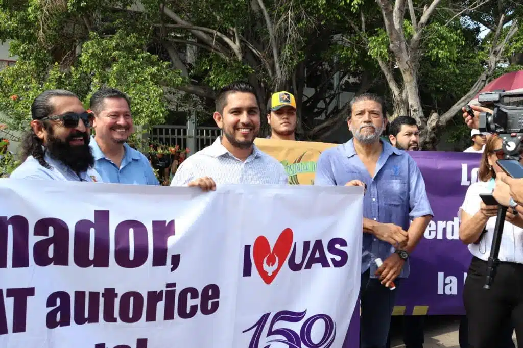 Maestros y alumnos de Facimar sosteniendo pancartas durante su manifestación a las afueras de Semarnat