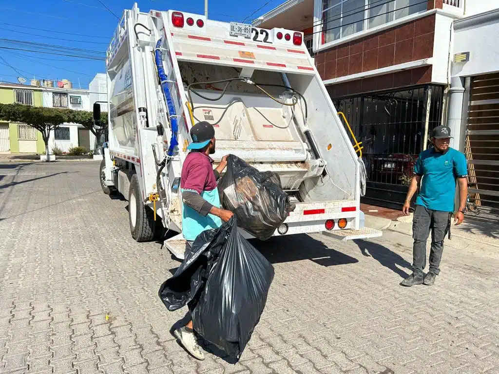 Hombres arrojando bolsas al camión recolector de basura