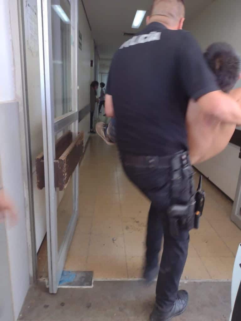 Elemento policiaco trasladando en brazos a Ricardo, quien se encontraba desmayado por aparente golpe de calor
