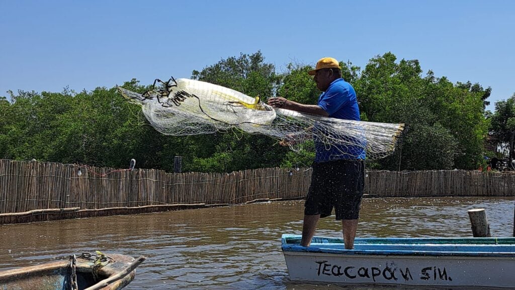 Pescador lanzando la red para atrapar camarón en el agua