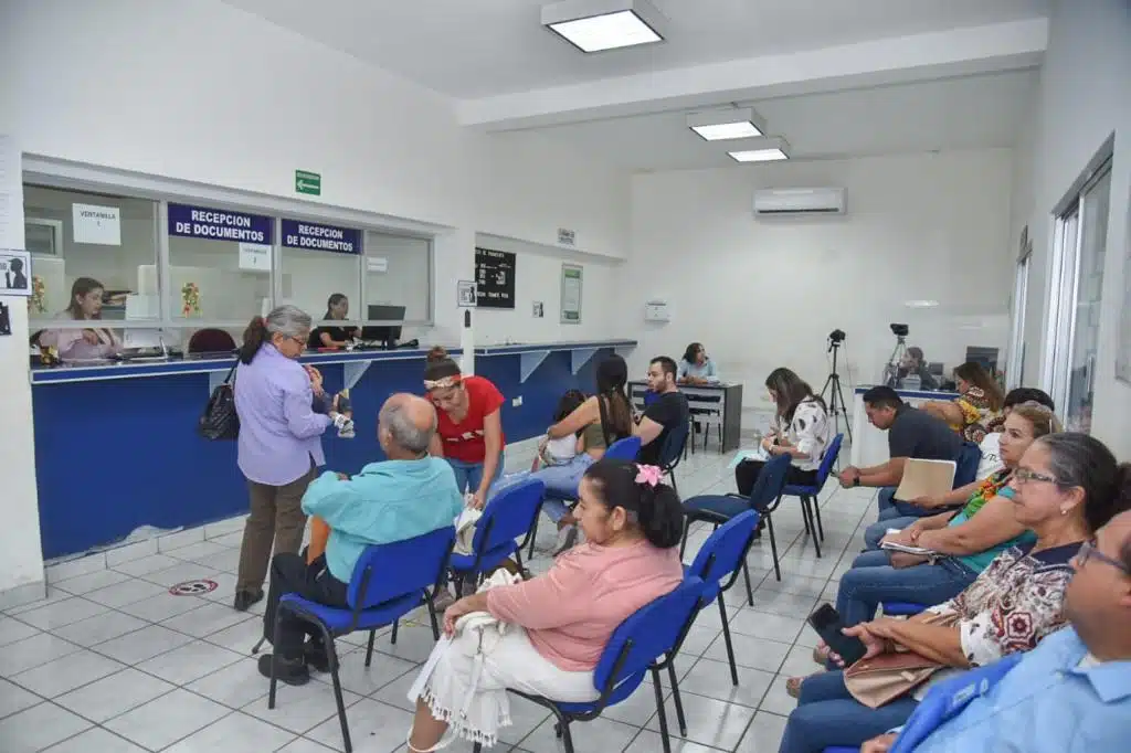 Personas sentadas en la oficina de Enlace de la Secretaría de Relaciones Exteriores (SER) del municipio de Ahome