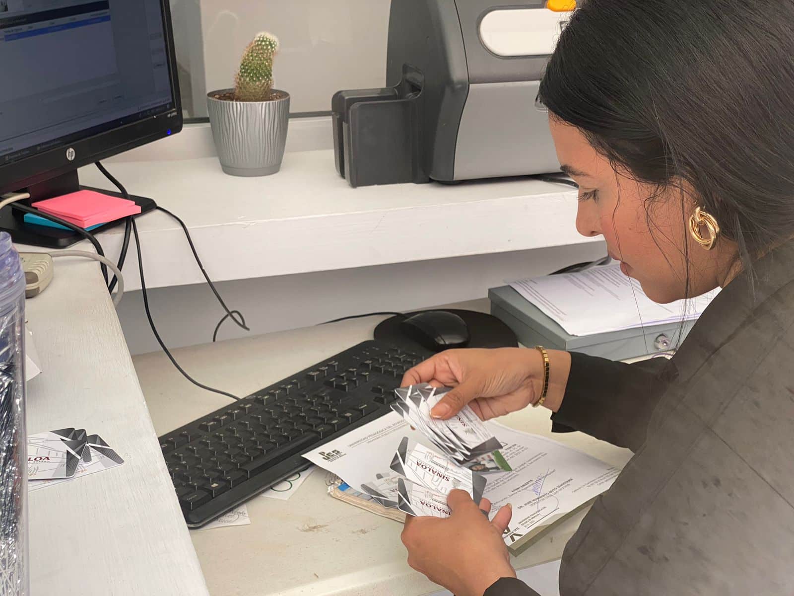 Encargada del módulo de atención sosteniendo algunas tarjetas inteligentes en sus manos