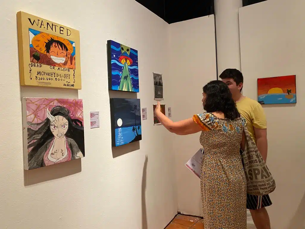 Asistentes observando las pinturas realizadas por los niños y adolescentes