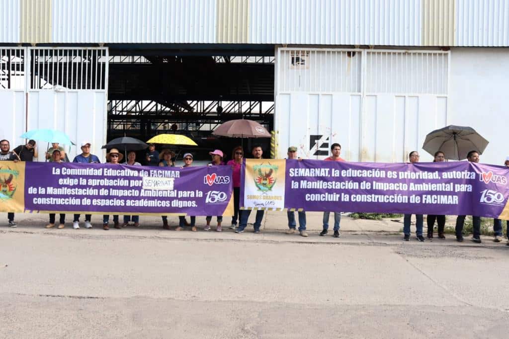 Maestros y alumnos de Facimar sosteniendo pancartas durante su manifestación a las afueras de Semarnat