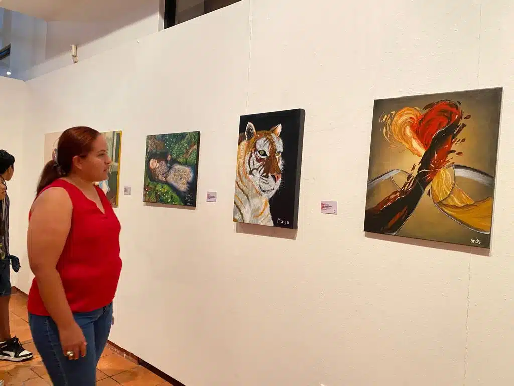 Asistentes observando las pinturas realizadas por los niños y adolescentes