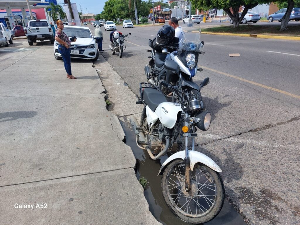 Motocicleta que conducía el lesionado. Atrás se encuentra un agente de tránsito y el vehículo que participó en el accidente