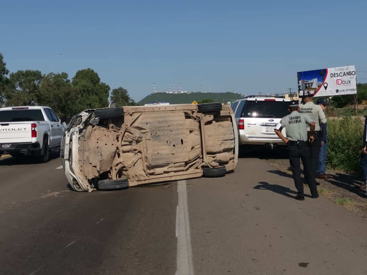 Automóvil volcado y personas de la Guardia Nacional a su derecha