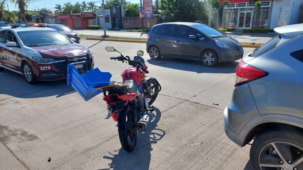 Una motocicleta, un carro de la policía municipal, un carro pasando por el lugar y la parte trasera de una camioneta