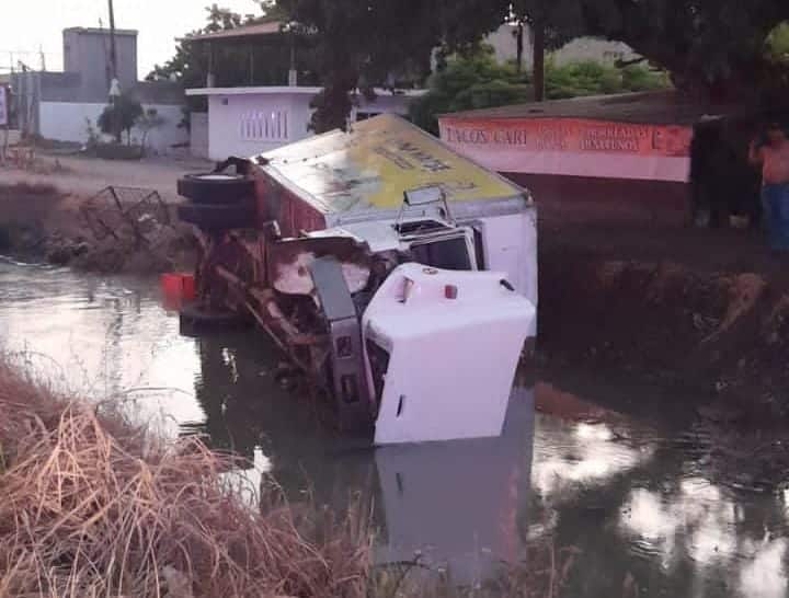Camión volcado sobre un canal con agua
