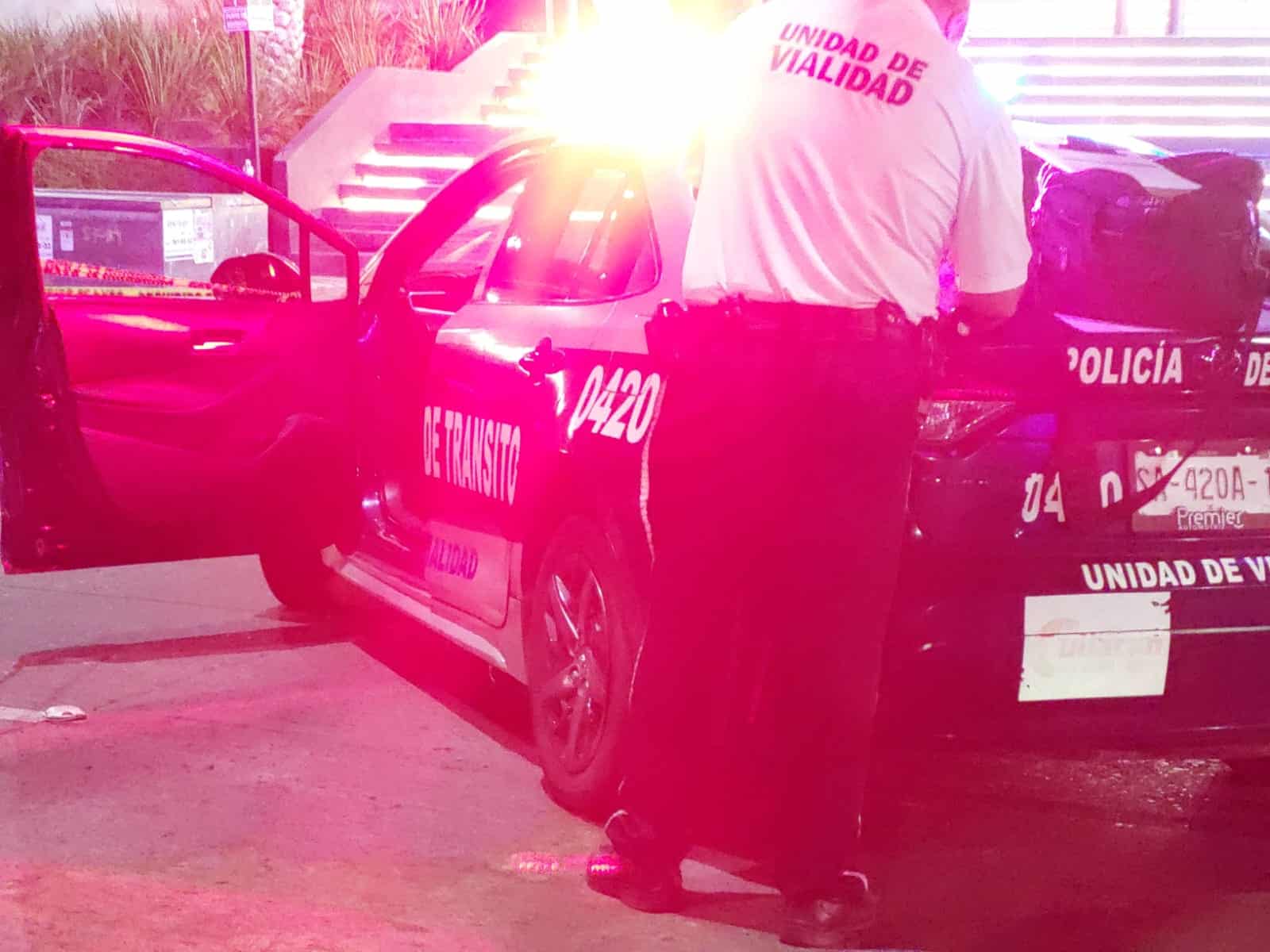 Agente de Tránsito detrás de su patrulla encendida durante la noche