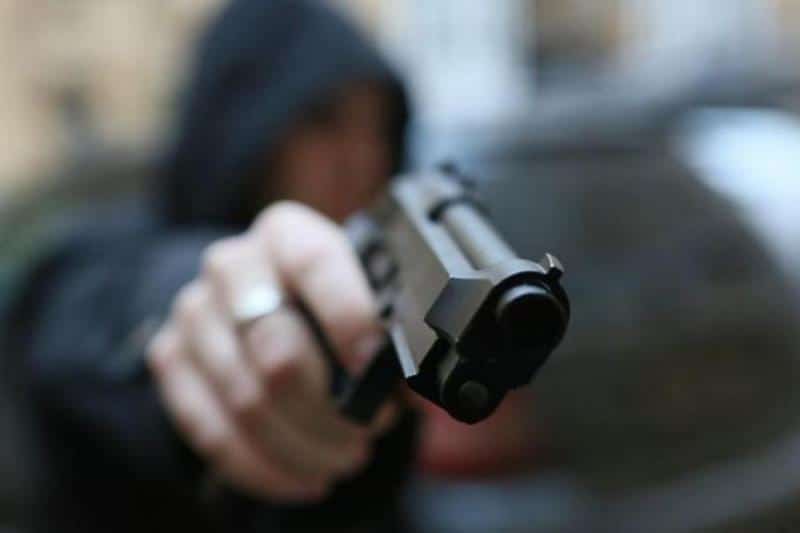 Sujeto apuntando hacia la cámara con una pistola