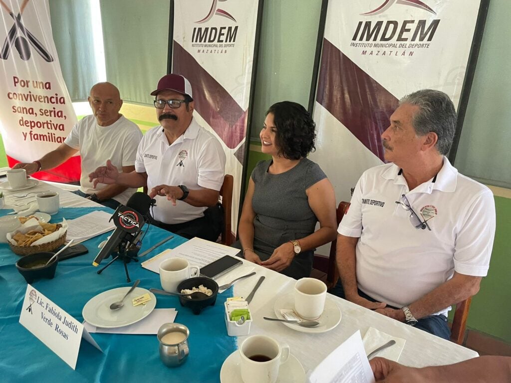 4 personas sentadas, una mesa con un mantel azul con blanco