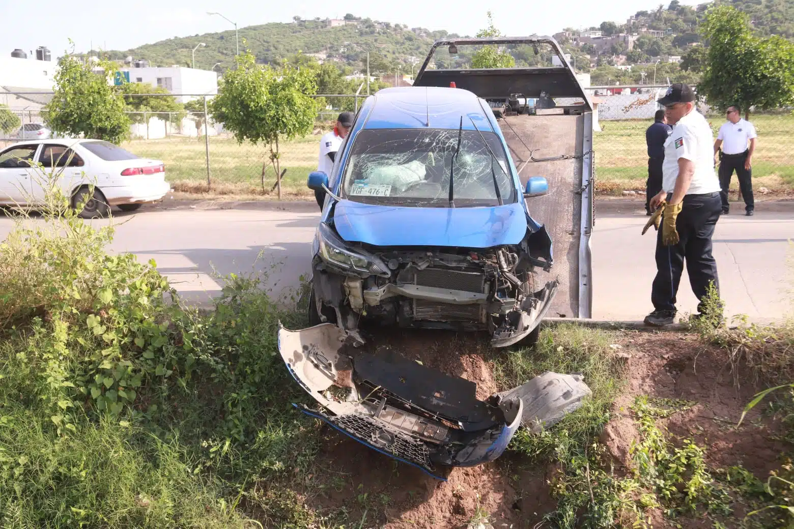Auto Nissan March azul sacado con grua de un canal tras accidente en Mazatlán