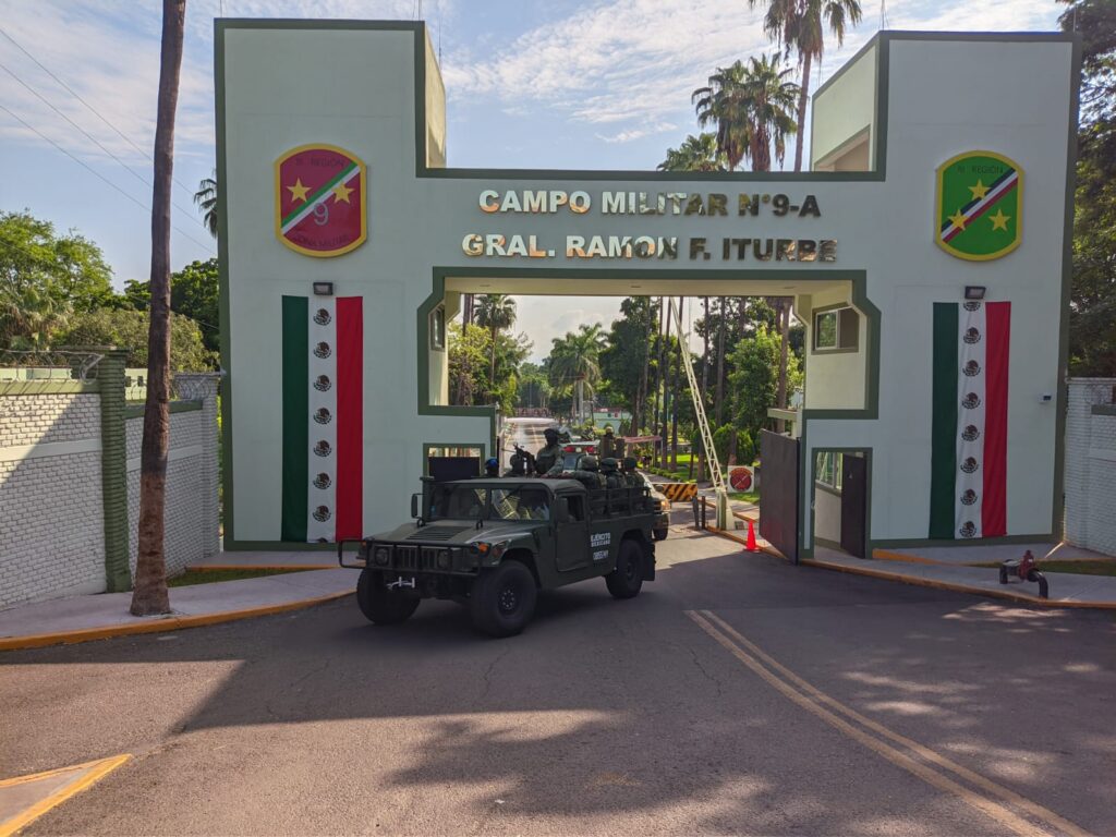 Fachada de la entrada de una zona militar y camionetas