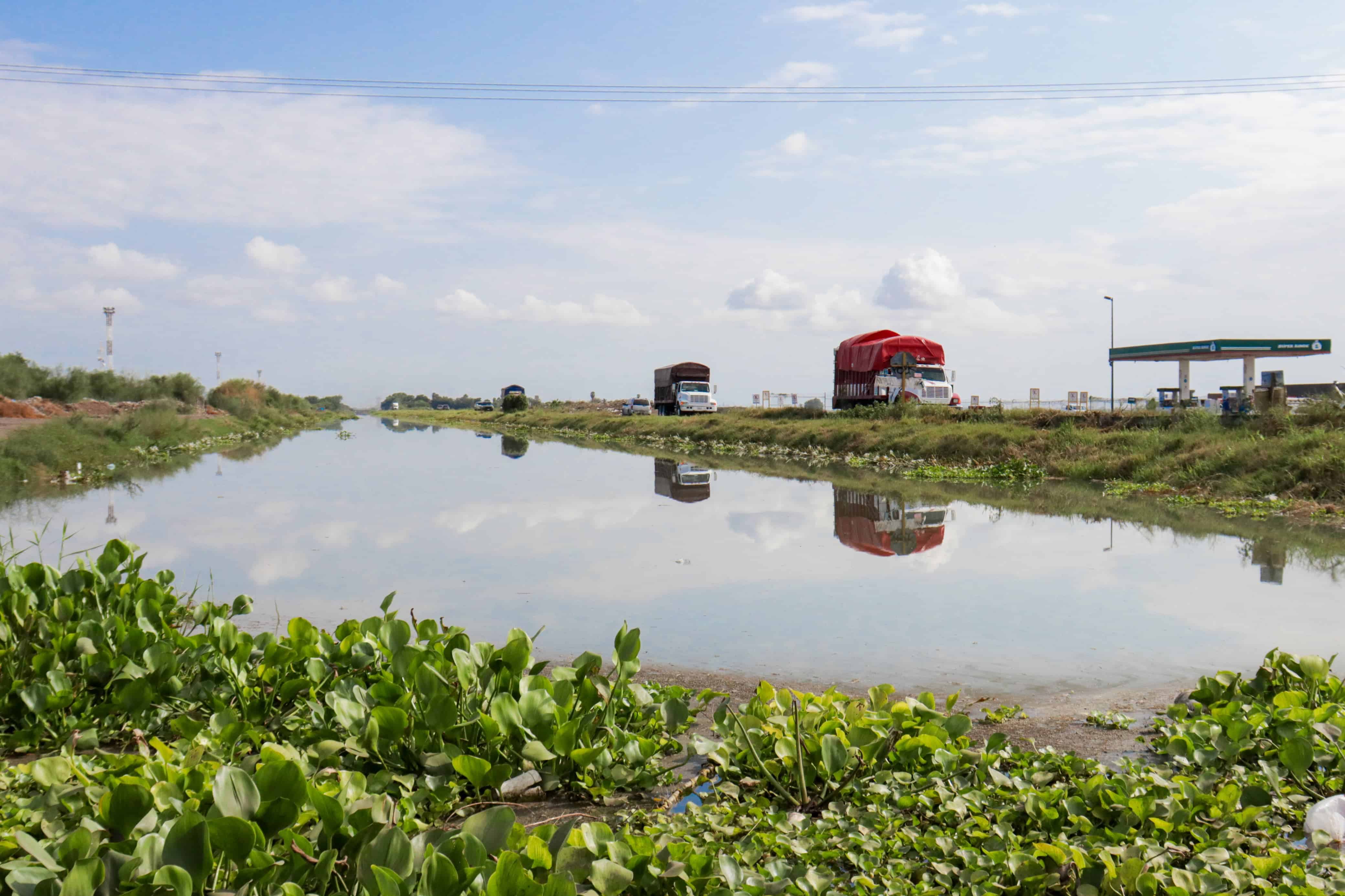 Canal con agua contaminada, y camiones