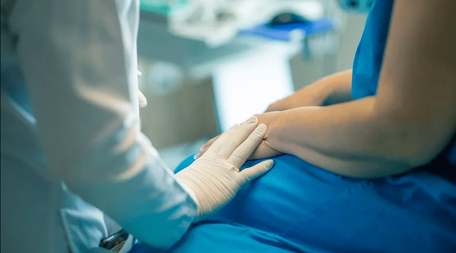 Médico poniendo su mano sobre la de una paciente en símbolo de apoyo