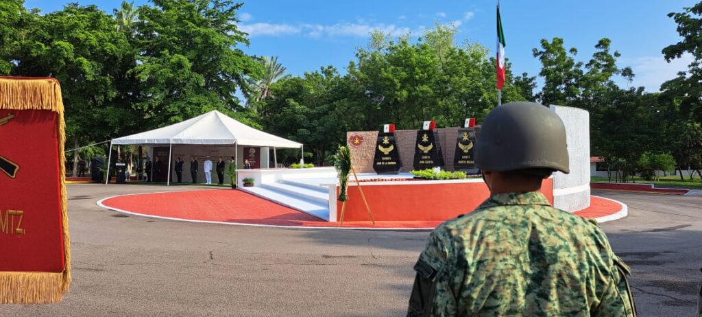 Una persona con uniforme de soldado y banderas de México