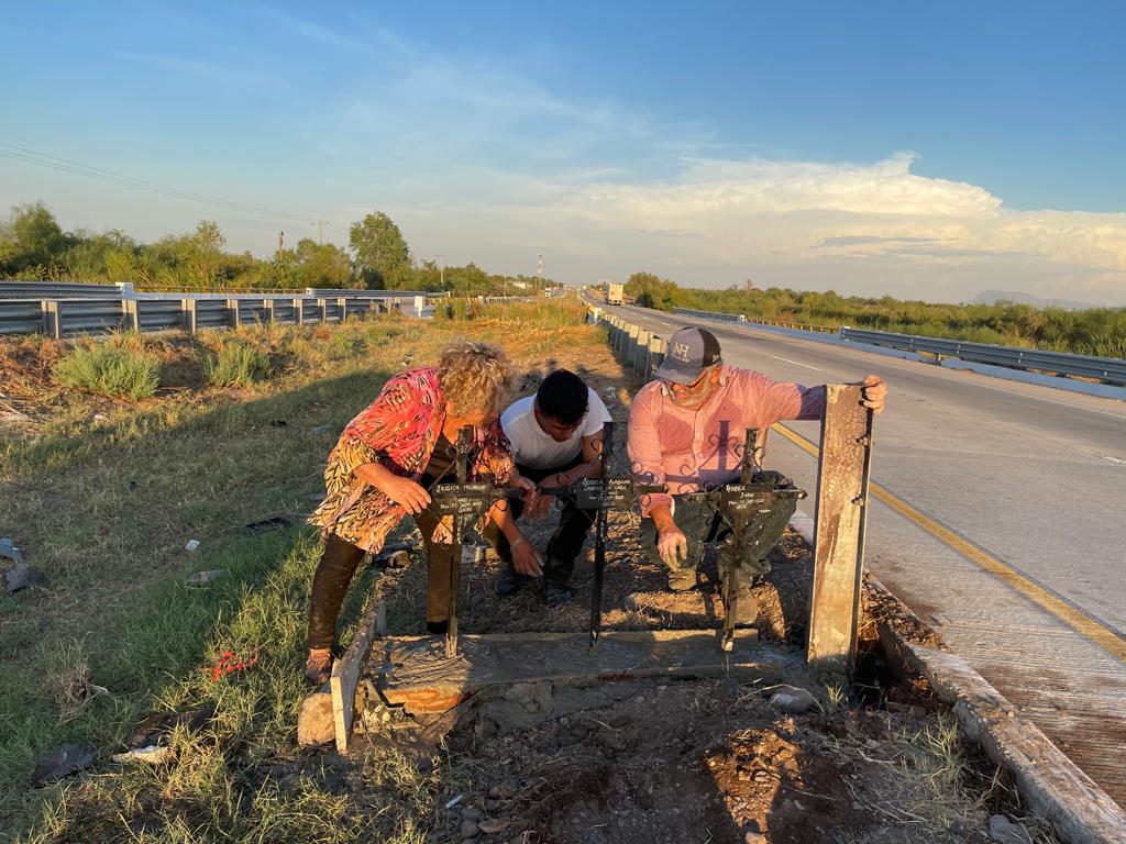 Personas poniendo cruces a la orilla de la carretera