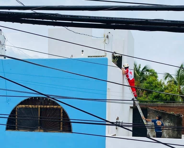 Una persona sobre una escalera, casa y cables