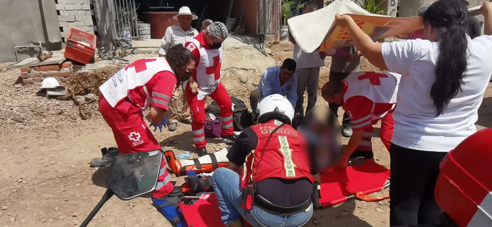 Paramédicos de cruz roja atendiendo a joven en ele suelo