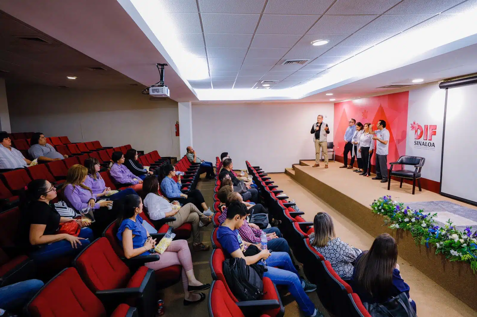 Personas sentadas en un auditorio y otras de pie