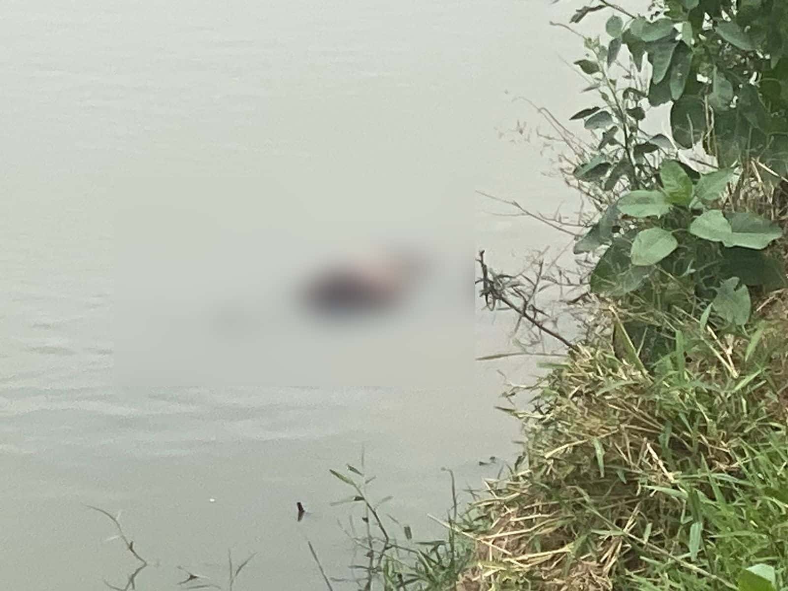 Cuerpo de una persona flotando en el agua de un canal