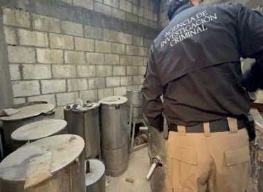 Una persona parada frente a unos tambos