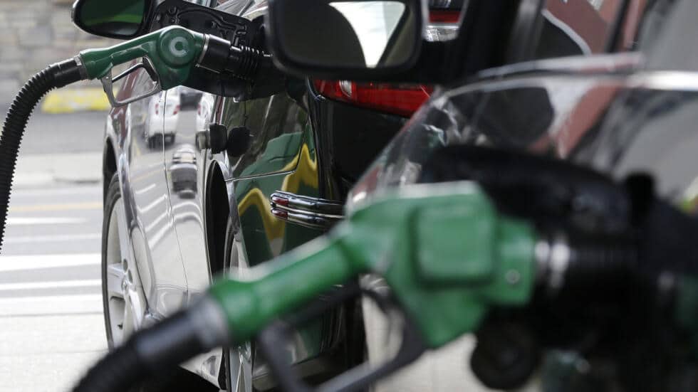 Manguera de una bomba de gasolinera cargando el tanque de un carro