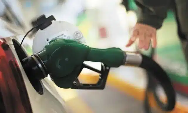 Auto con la manguera de una bomba de gasolina cargando combustible