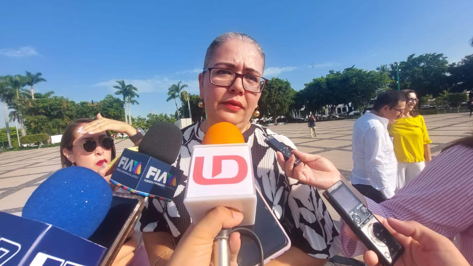Una persona con lentes y micrófonos de los medios de comunicación