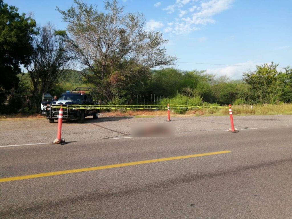 Una persona tirada en la orilla de la carretera, cinta amarilla delimitando el cuerpo