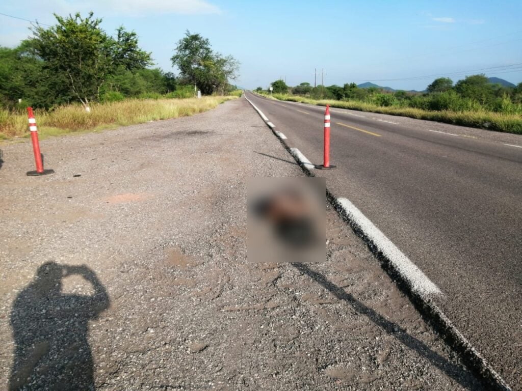 Una persona tirada en la orilla de la carretera, cinta amarilla delimitando el cuerpo