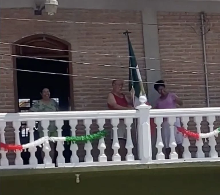 Momento que hombre saca bandera de México del balcón de su casa