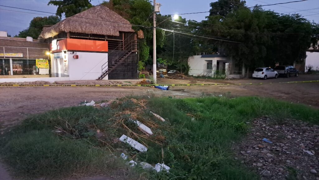 Imagen tomada de lejos de un hombre tirado en la calle cubierto con una sábana azul tras ser asesinado en Culiacán