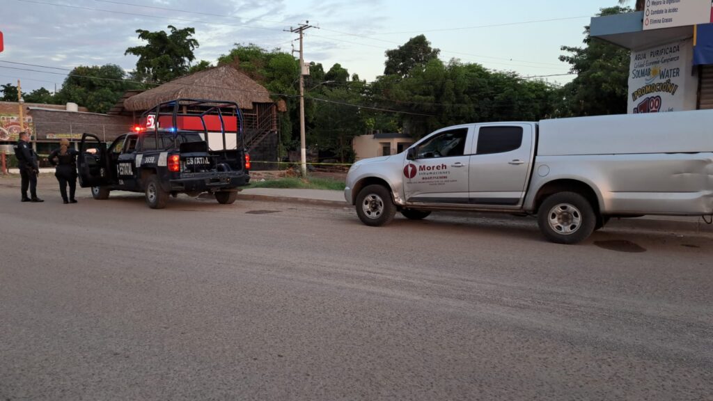 Policías municipales en una patrulla y camioneta funeraria en zona donde se registró un homicidio en Culiacán