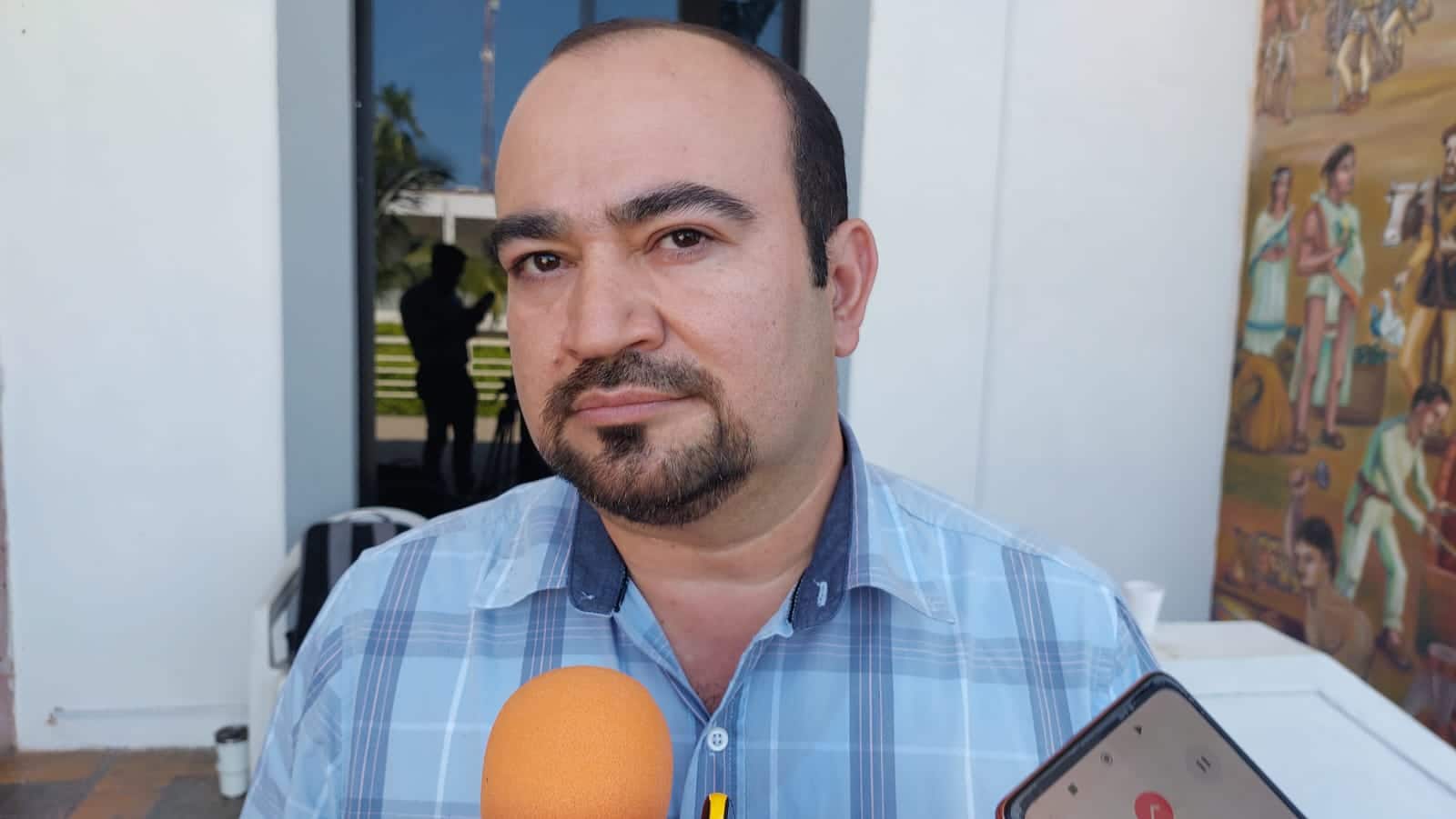 Una persona y parte de un micrófono de un medio de comunicación