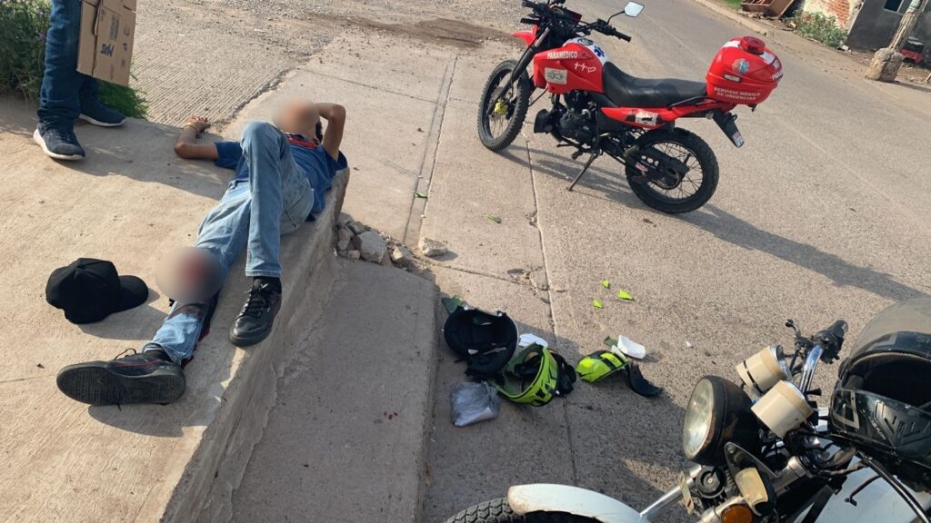 Una persona acostada, una motocicleta y un casco quebrado