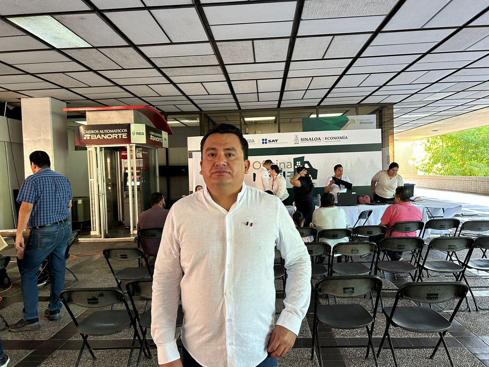Una persona posando para una foto y al fondo sillas y más personas