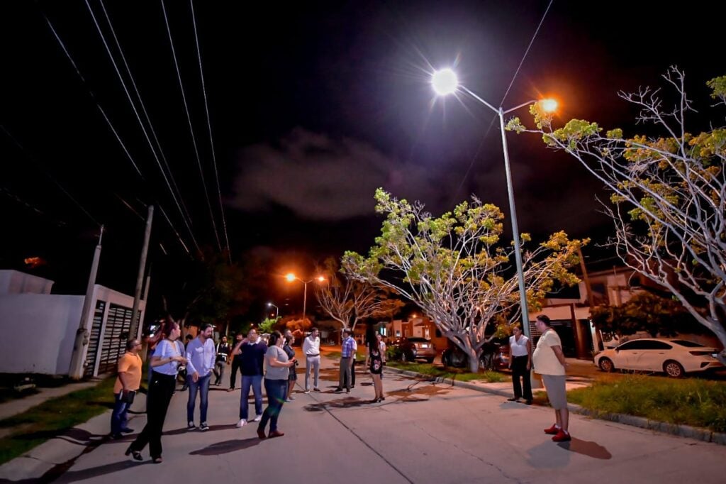 Personas en una calle y una lámpara alumbrando