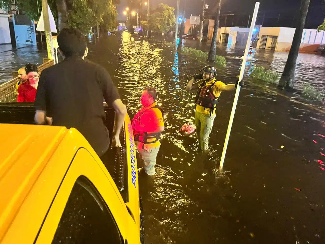 Avenida inundada, personas y parte de una camioneta