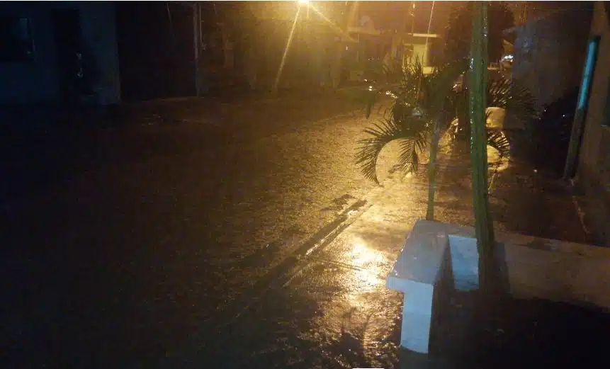 Lluvia, calle pavimentada encharcada y le corre agua