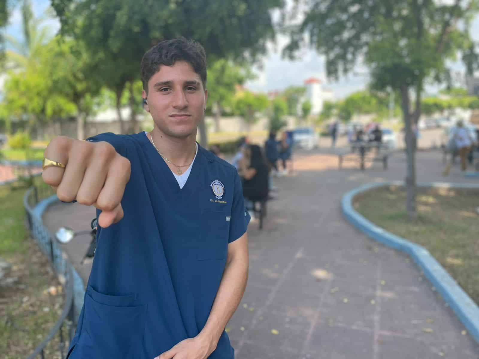 Una persona posando para una foto con un brazo arriba y el puño cerrado como boxeador y árboles al fondo