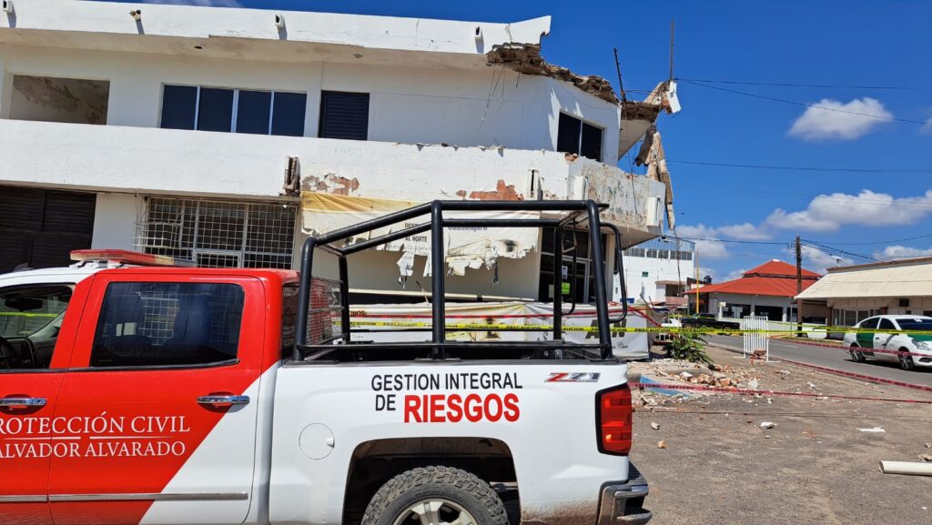 Camioneta de protección cicivl frente a un edificio deteriorado