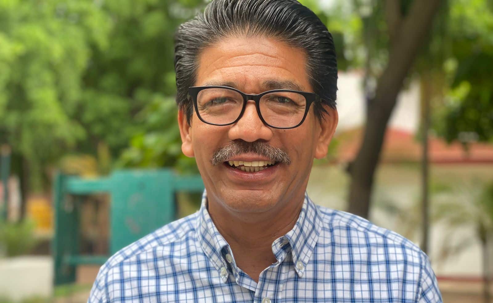 Una persona con lentes y bigote sonriendo para una foto