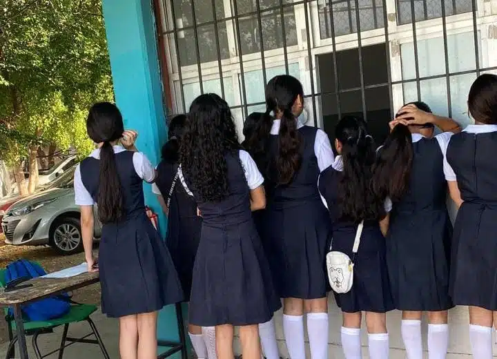 Alumnas paradas mirando por ventana de aula