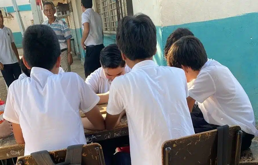 Niños escribiendo en mesa fuera del aula
