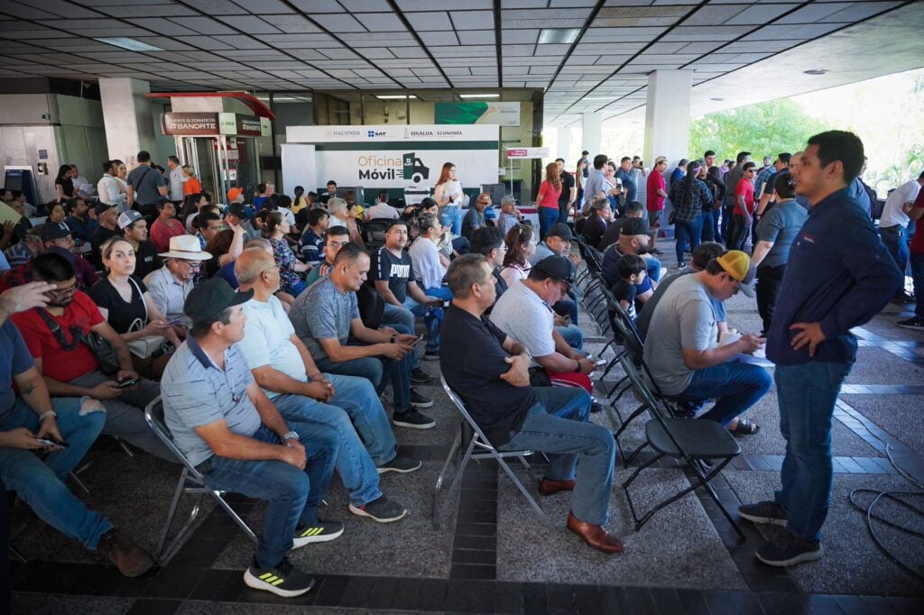 Ciudadanos sentados esperando su turno en la oficina móvil del SAT