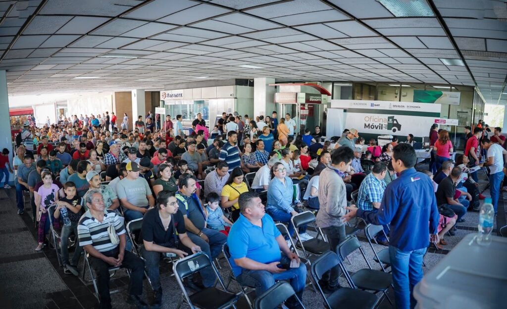 Ciudadanos sentados esperando su turno en la oficina móvil del SAT