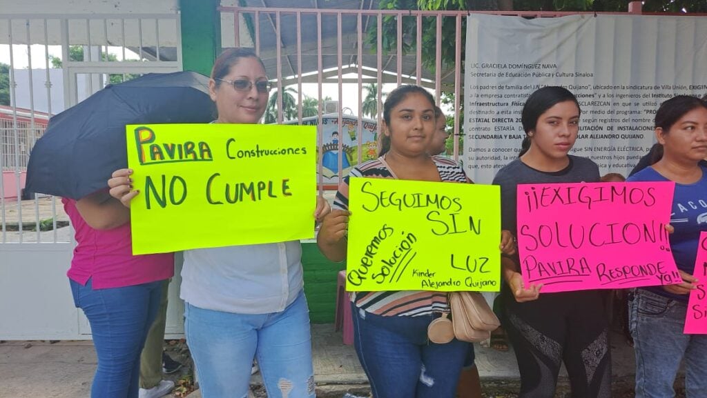 Personas con cartulinas a fuera de un kínder